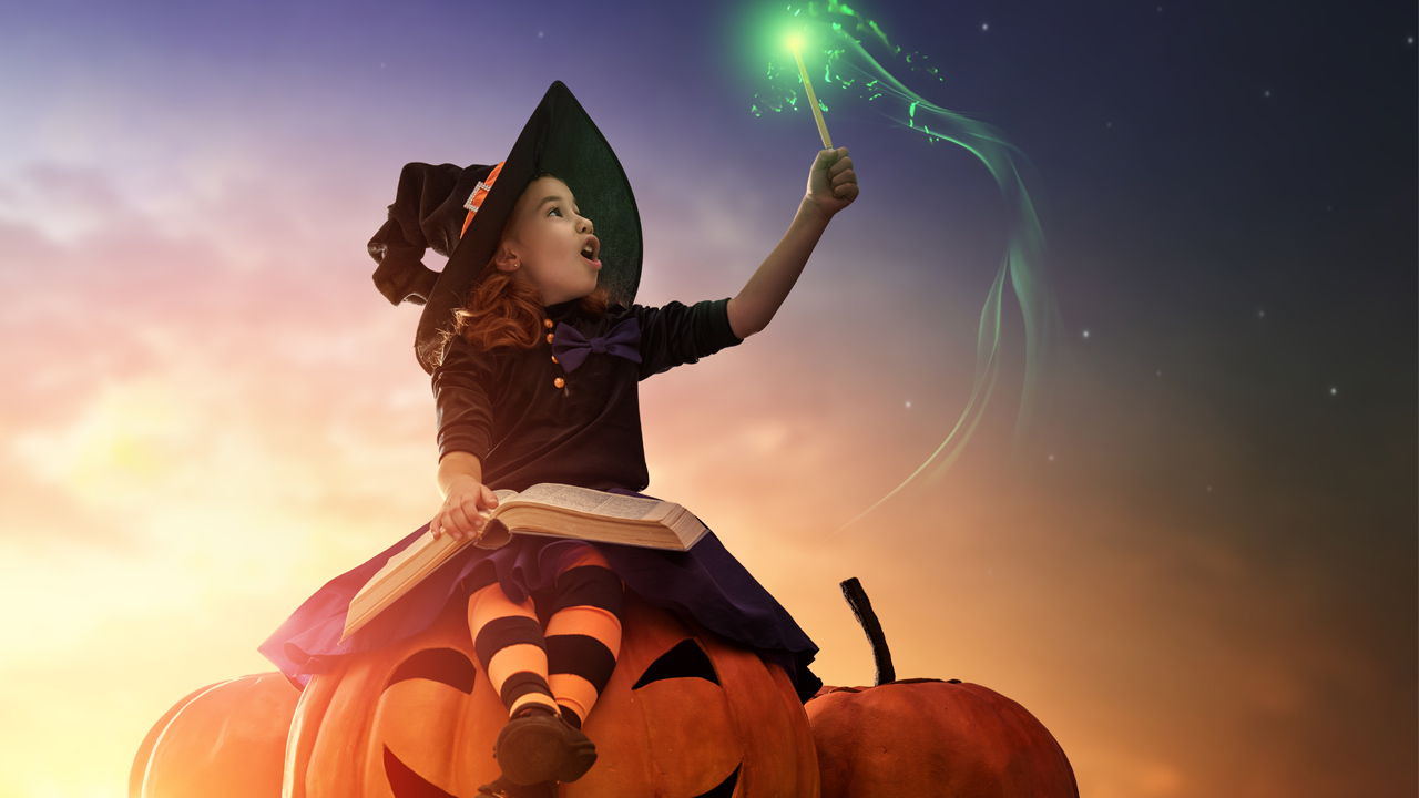 Halloween girl sitting on pumpkins holding a magic wand